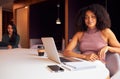 Portrait Of Businesswoman With Laptop At Socially Distanced Meeting In Office During Health Pandemic