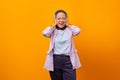 Portrait of a businesswoman laughing covering her ears isolated on yellow background