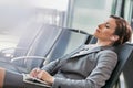 Portrait of businesswoman listening to music on smartphone while sleeping and waiting for boarding in airport Royalty Free Stock Photo
