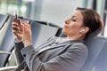 Portrait of businesswoman listening to music on smartphone while waiting for boarding in airport Royalty Free Stock Photo