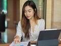 Portrait of businesswoman looking on financial paper with tablet