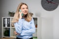 Portrait of businesswoman with mobile phone standing at office. young Caucasian businesswoman holding mobile phone in office. Royalty Free Stock Photo