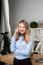 Portrait of businesswoman with mobile phone standing at office. young Caucasian businesswoman holding mobile phone in office. Royalty Free Stock Photo