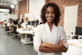 Portrait Of Businesswoman In Modern Open Plan Office With Business Team Working In Background