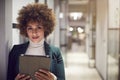 Portrait Of Businesswoman Standing In Corridor Of Modern Office Using Digital Tablet In Evening