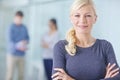 Portrait of a businesswoman standing with her arms crossed, smiling and looking at the camera while her colleagues stand Royalty Free Stock Photo