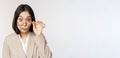 Portrait of businesswoman take-off glasses and looking surprised at camera, standing over white background Royalty Free Stock Photo