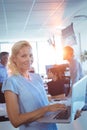 Portrait of businesswoman working on laptop with team in background Royalty Free Stock Photo