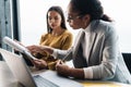 Portrait of businesswomen sitting by desk while working in office