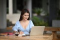 Portrait of bussiness woman smiling while working on laptop and take note.