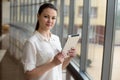 Portrait of busy business woman working on ipad while standing by window in office. Small business. Beautiful young Royalty Free Stock Photo