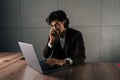 Portrait of busy businessman talking smartphone typing laptop, having multitask in office, looking to screen. Successful