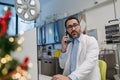 Portrait of busy doctor phone calling in emergency room, decorated for Christmas. Mature male doctor working a Royalty Free Stock Photo