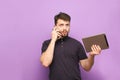 Portrait of a busy man standing on a blue background with a tablet in his hands and talking on the phone.Business man with gadgets Royalty Free Stock Photo