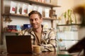 Portrait of cafe owner, young man sitting in coffee shop with laptop, working on data project, looking at screen Royalty Free Stock Photo