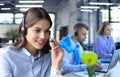 Portrait of call center worker accompanied by her team. Smiling customer support operator at work Royalty Free Stock Photo