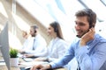 Portrait of call center worker accompanied by his team. Smiling customer support operator at work