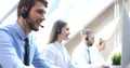 Portrait of call center worker accompanied by his team. Smiling customer support operator at work Royalty Free Stock Photo