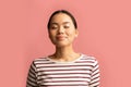 Portrait Of Calm Asian Woman Standing With Closed Eyes On Pink Background