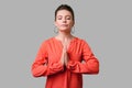 Portrait of calm beautiful girl with bun hairstyle, big earrings and in red blouse. indoor studio shot isolated on gray background Royalty Free Stock Photo