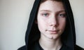 Portrait of a calm blue-eyed teenage boy in a black hood