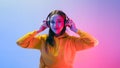 Portrait of a calm Caucasian woman wearing a yellow hoodie sitting and wearing wireless headphones, and posing .