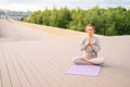 Portrait of calm Caucasian young woman practicing yoga performing namaste pose with closed eyes outside in city park. Royalty Free Stock Photo