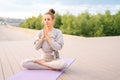 Portrait of calm Caucasian young woman practicing yoga performing namaste pose with closed eyes outside in city park. Royalty Free Stock Photo