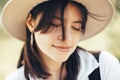 Portrait of calm hipster girl with backpack traveling on top of sunny mountain. Stylish woman in hat enjoying hiking in mountains