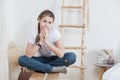 Portrait of calm pre teen girl dressing blue jeans and white t-shirt, sitting on bench in her room Royalty Free Stock Photo