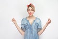 Portrait of calm relaxed beautiful young woman in casual blue denim shirt with makeup and red headband standing with raised arms Royalty Free Stock Photo