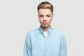 Portrait of calm serious handsome young man in light blue shirt standing and looking at camera with serious face Royalty Free Stock Photo