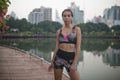 Calm young woman standing outside in city park with skyscrapers on background