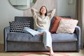 Portrait of carefree asian woman enjoying day-off, sitting on sofa and smiling pleased, relaxing in house on weekends