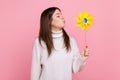 Portrait of carefree brunette woman blowing at paper windmill, playing with pinwheel toy on stick. Royalty Free Stock Photo