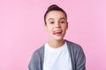 Portrait of carefree childish brunette girl showing tongue, disobedient teenager making face. on pink background