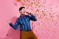 Portrait of carefree handsome guy arm hold wired microphone shout sing flying confetti isolated on pink color background Royalty Free Stock Photo