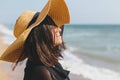 Portrait of carefree happy woman with windy hair in hat relaxing on sunny beach at sea. Summer vacation. Stylish calm young female Royalty Free Stock Photo