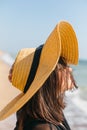 Portrait of carefree happy woman with windy hair in hat relaxing on sunny beach at sea. Summer vacation. Stylish calm young female Royalty Free Stock Photo