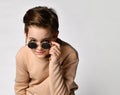 Portrait of carefree nice smiling boy child touching sunglasses over studio wall