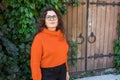 Portrait of carefree young woman smiling with big door and copy space background. Cheerful latin girl wearing eyeglasses Royalty Free Stock Photo