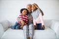 Portrait of caring african mother hugging daughters on couch