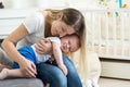 Portrait of young caring mother embracing and calming down her crying baby boy Royalty Free Stock Photo