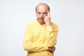 Portrait of casual mature man in yellow shirt thinking and looking puzzled Royalty Free Stock Photo