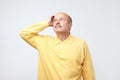 Portrait of casual mature man in yellow shirt thinking and looking puzzled Royalty Free Stock Photo