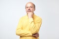 Portrait of casual mature man in yellow shirt thinking and looking puzzled Royalty Free Stock Photo