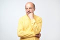 Portrait of casual mature man in yellow shirt thinking and looking puzzled Royalty Free Stock Photo