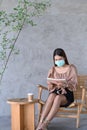 Casual woman in face mask reading book at cafe. Royalty Free Stock Photo