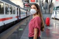 Portrait of casual woman waiting train with KN95 FFP2 protective mask at train station Royalty Free Stock Photo