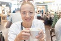 Portrait of a casual young blond woman having a cup of coffee, sitting in cafe indoors of an airport, station, food Royalty Free Stock Photo